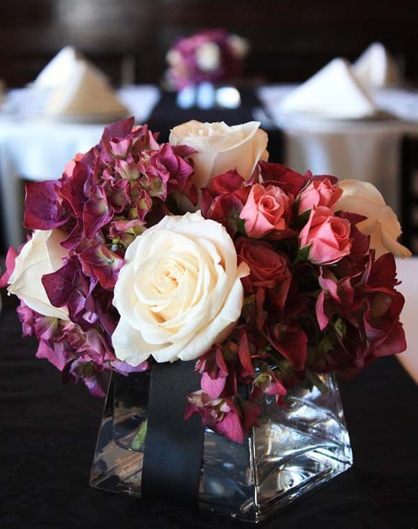 A vase filled with roses and hydrangea sits on a table