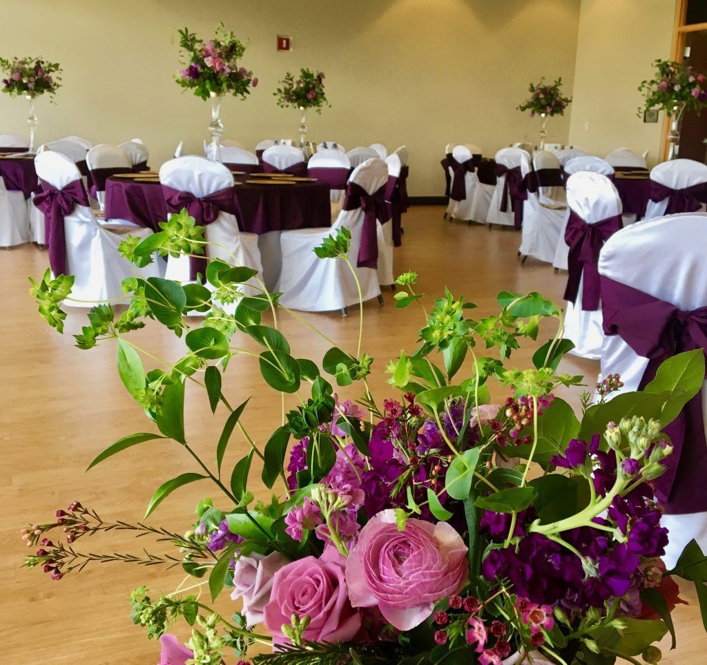 A room with tables and chairs decorated in purple and white