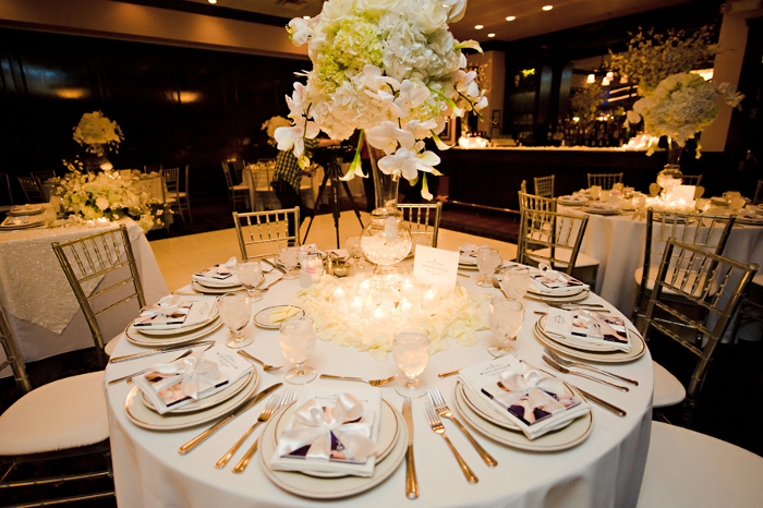 A table set for a wedding reception with white plates and silverware
