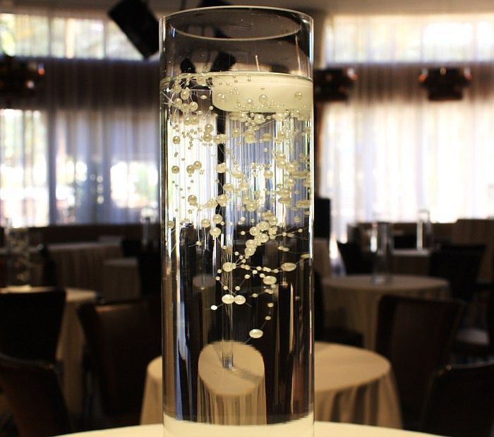 A tall glass filled with water and bubbles sits on a table