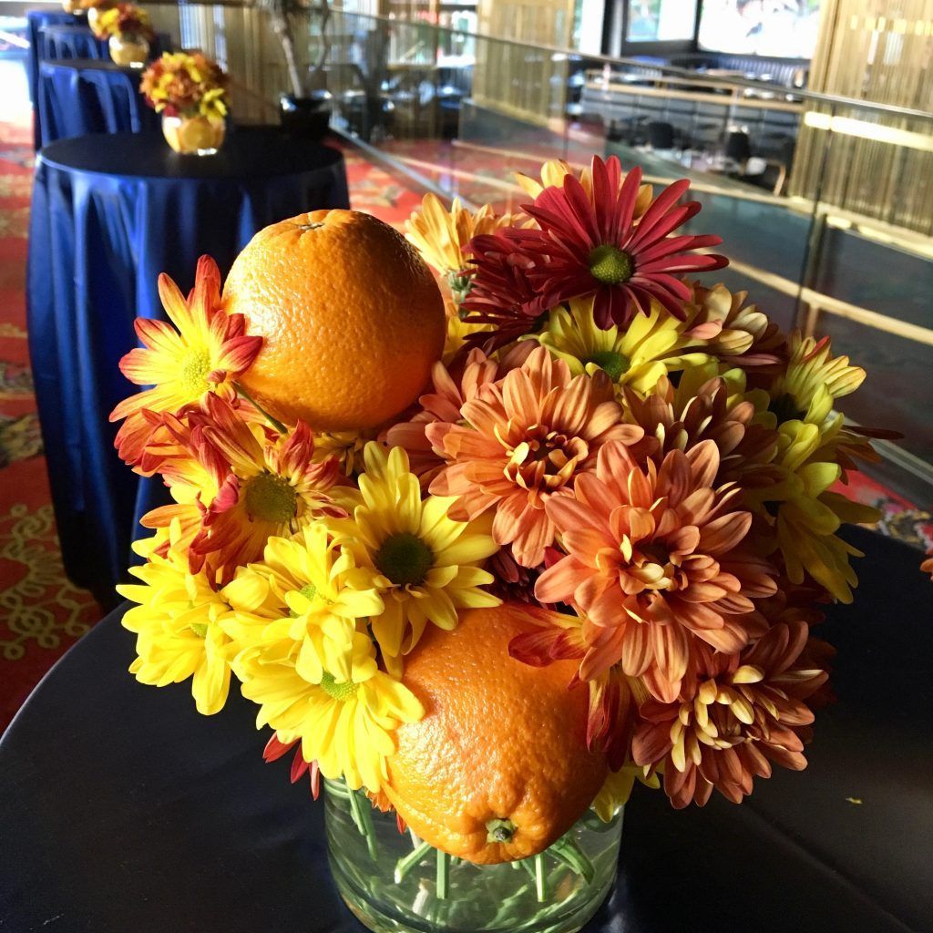 A vase filled with flowers and oranges on a table