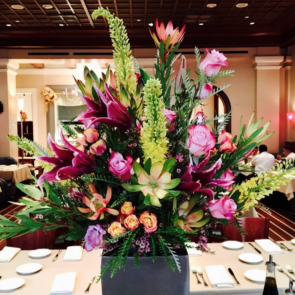 A large vase of flowers sits on a table in a restaurant
