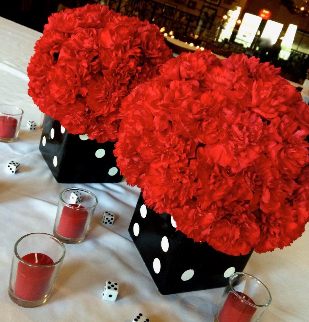 Two vases filled with red flowers and candles on a table