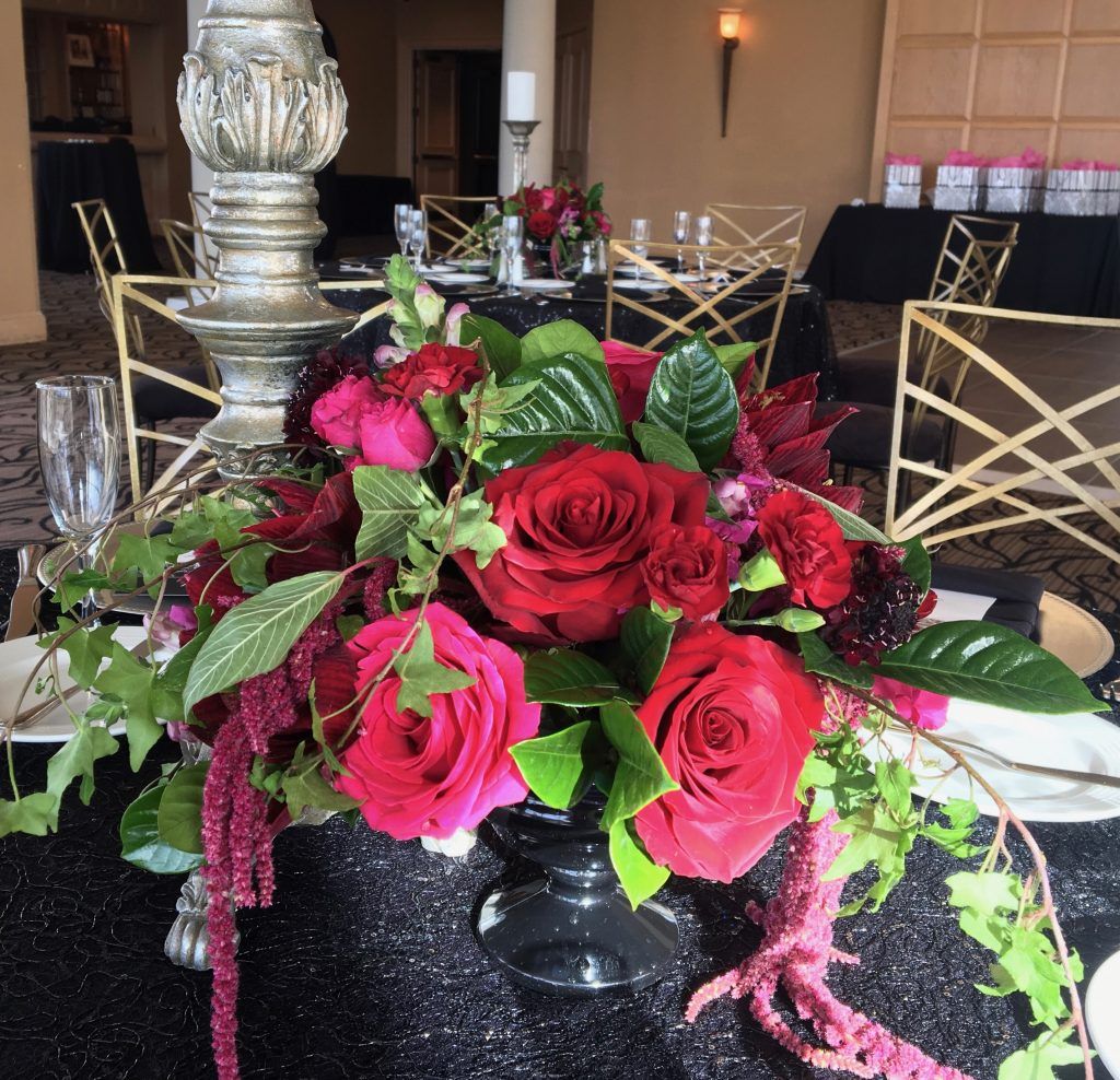 A black vase filled with red roses sits on a table