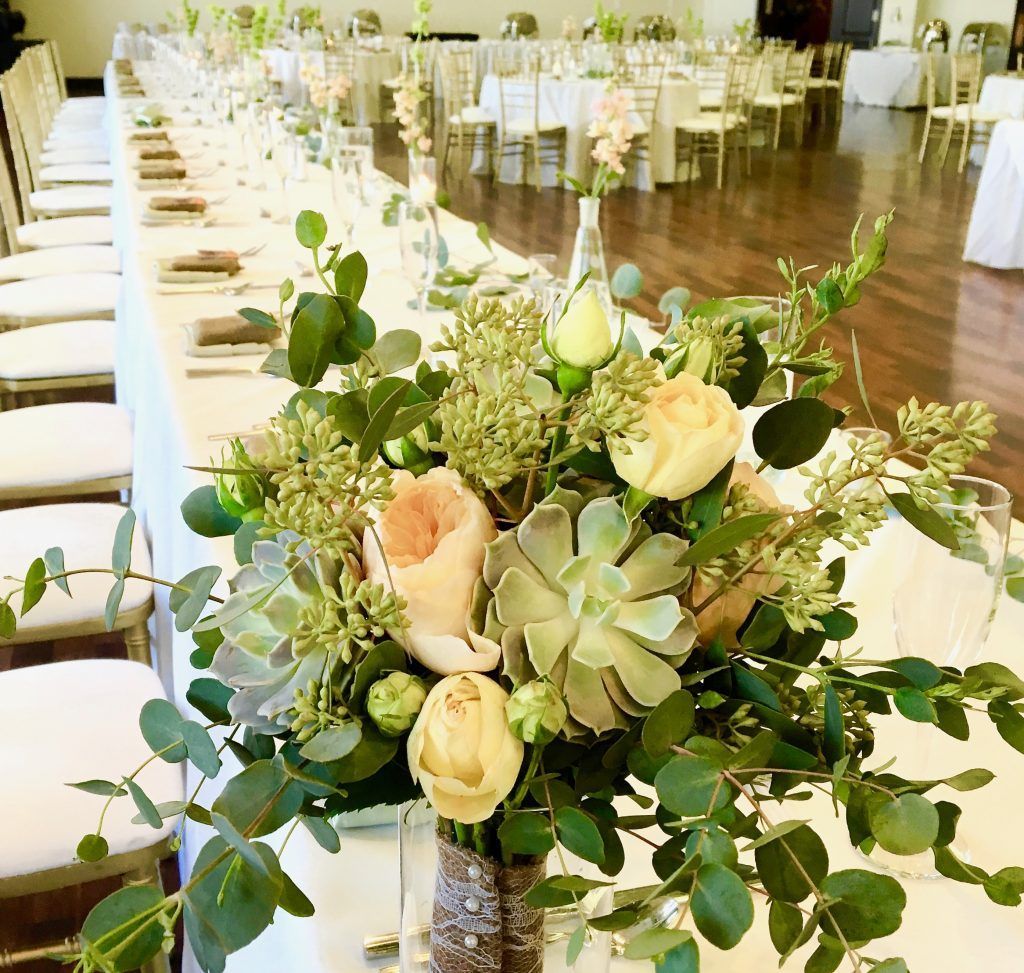 A bouquet of flowers is sitting on a long table.