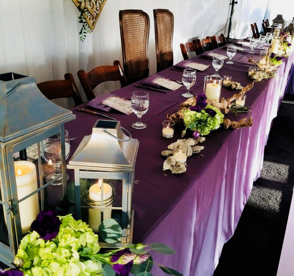 A long purple table with candles and flowers on it