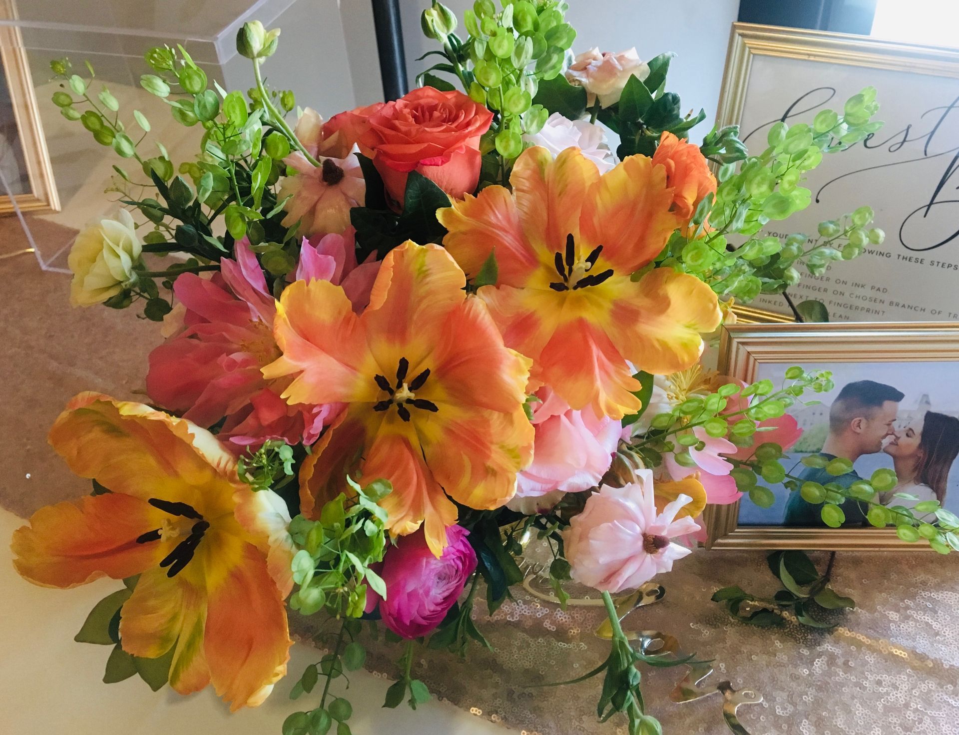 A bouquet of flowers sits on a table next to a picture of a man and woman kissing.