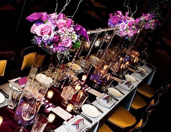 A long table with purple flowers and candles on it