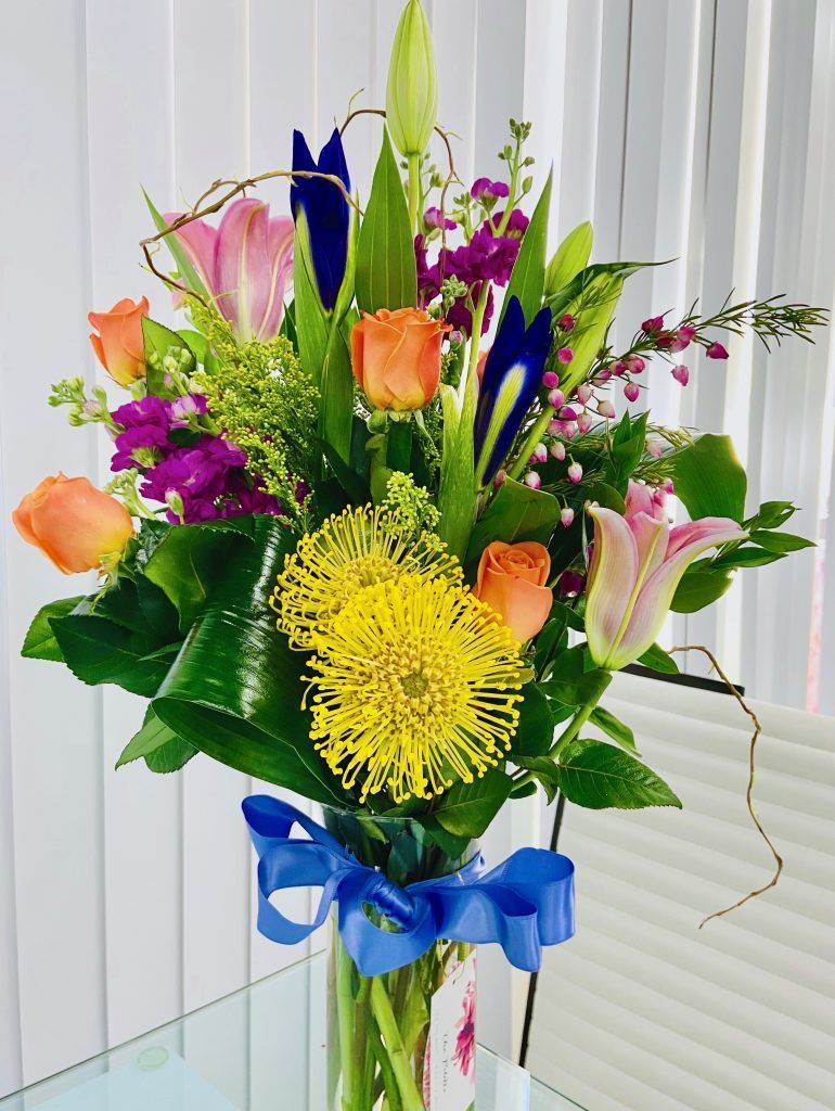 A vase filled with flowers and a blue bow