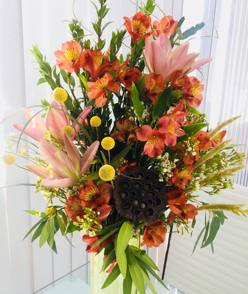 A vase filled with flowers and leaves on a table