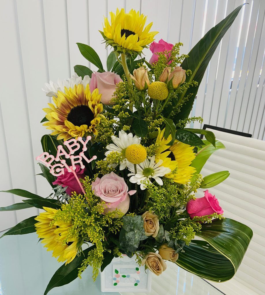 A bouquet of flowers with a sign that says baby girl