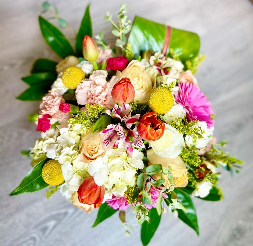A bouquet of flowers is sitting on a wooden table.