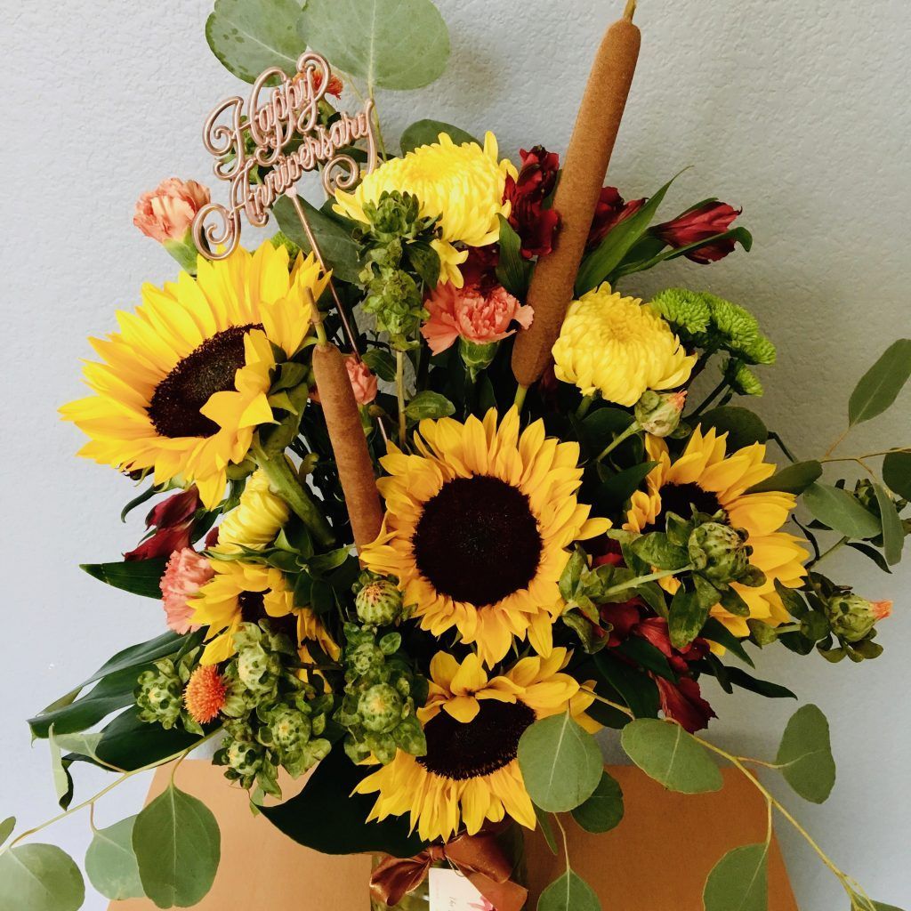 A bouquet of sunflowers and other flowers with a happy birthday topper