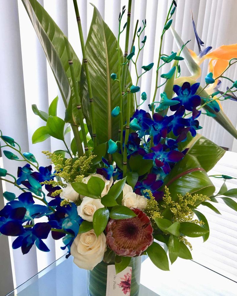 A vase filled with blue and white flowers and greenery