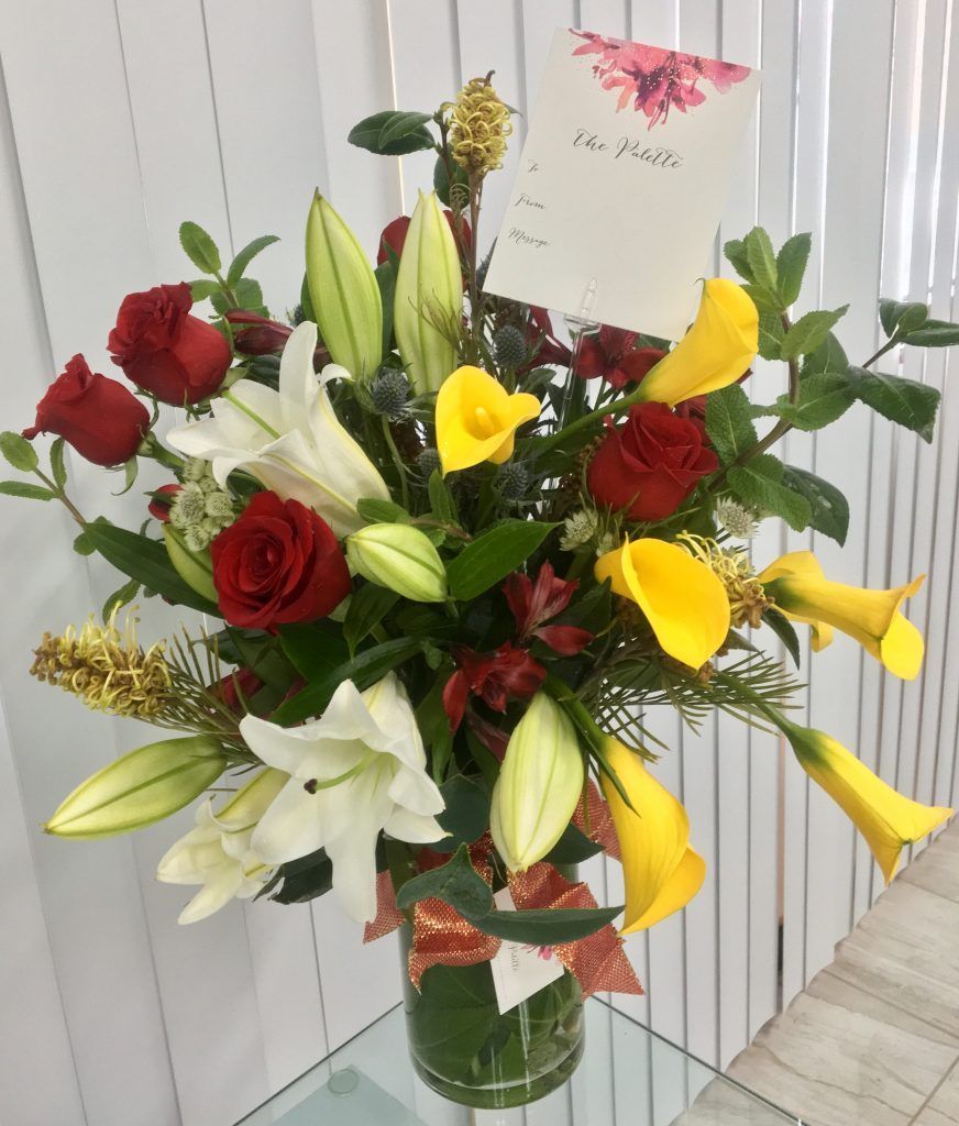 A bouquet of flowers in a vase with a card attached to it