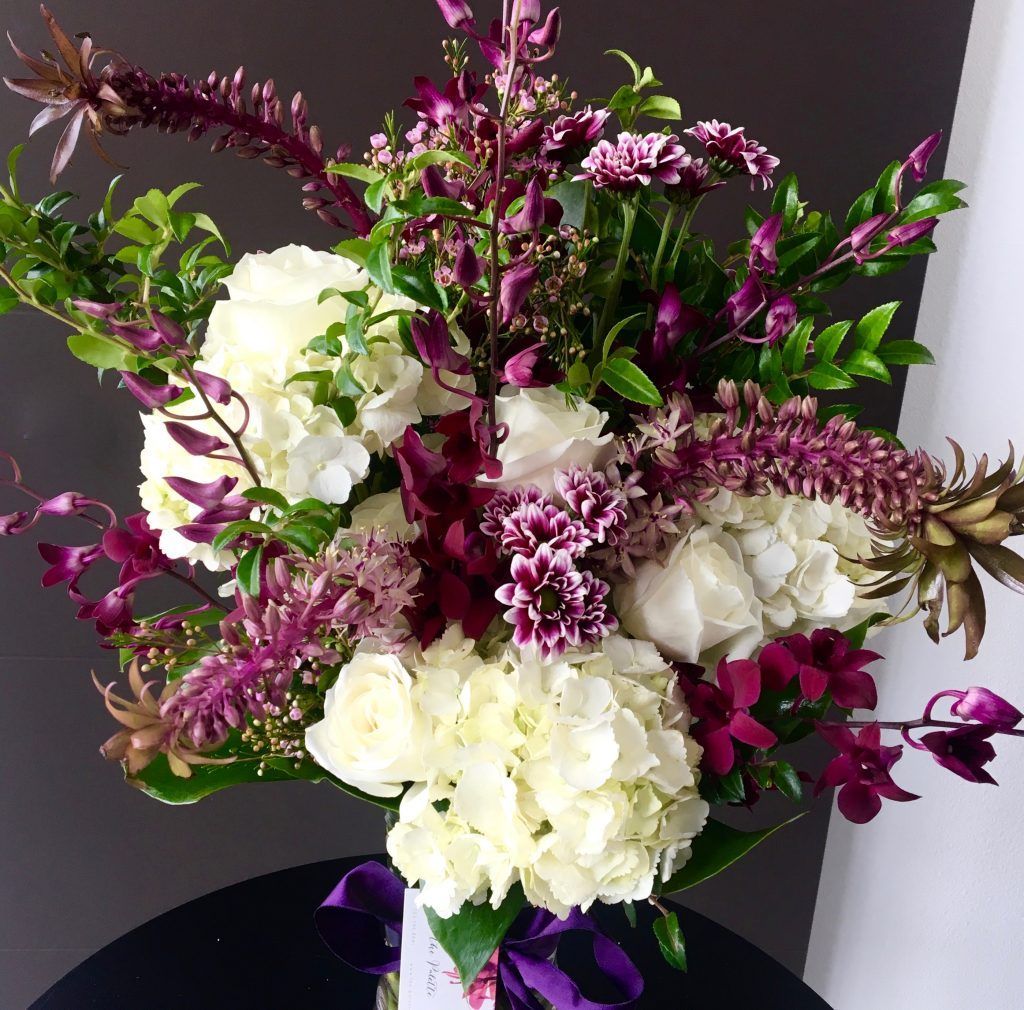 A vase filled with purple and white flowers on a table