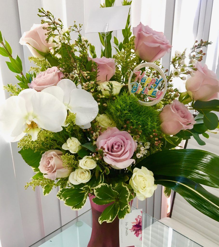 A vase filled with pink roses and white flowers