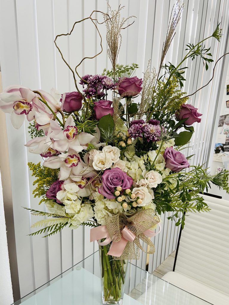 A vase filled with purple and white flowers is sitting on a table.