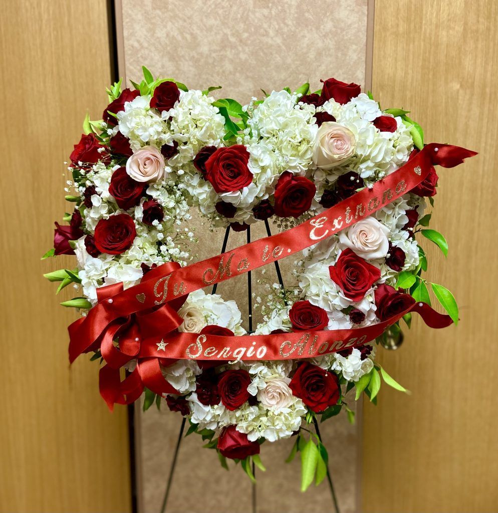A heart shaped wreath with red roses and white flowers
