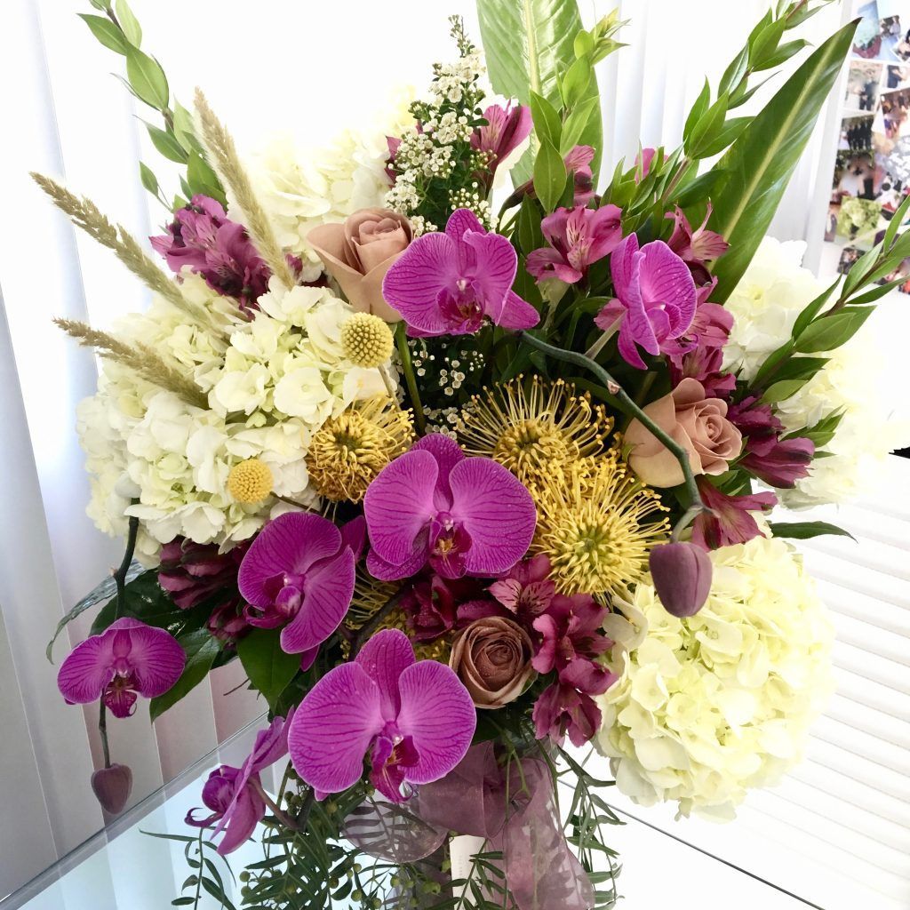 A vase filled with purple and white flowers is on a table.