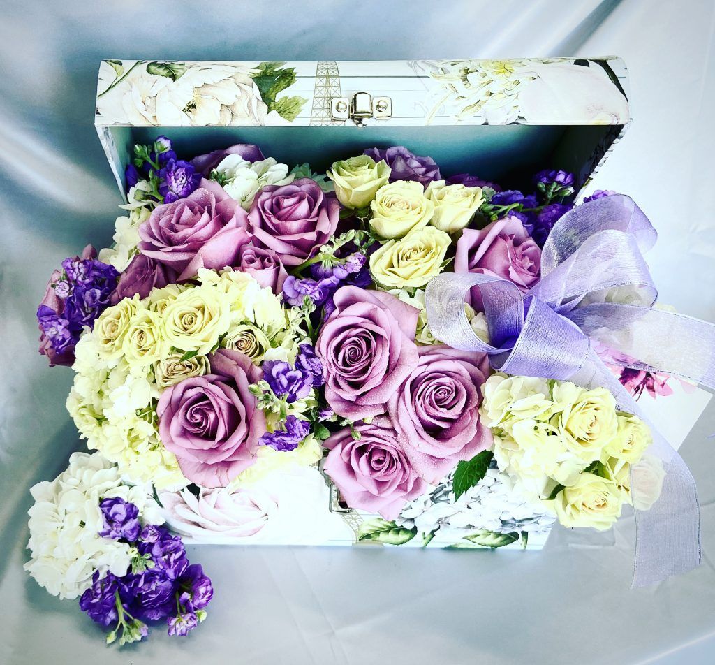A box filled with purple and yellow flowers on a table.