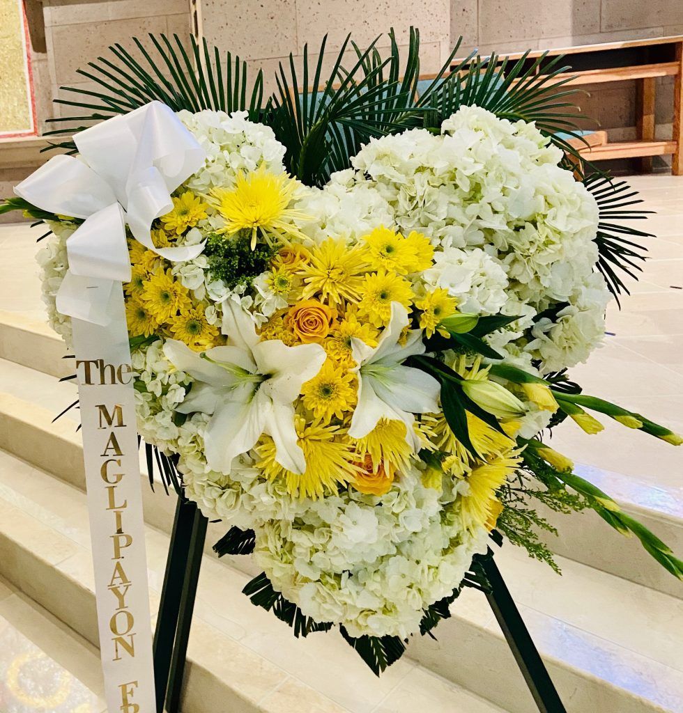 A heart shaped wreath with yellow and white flowers