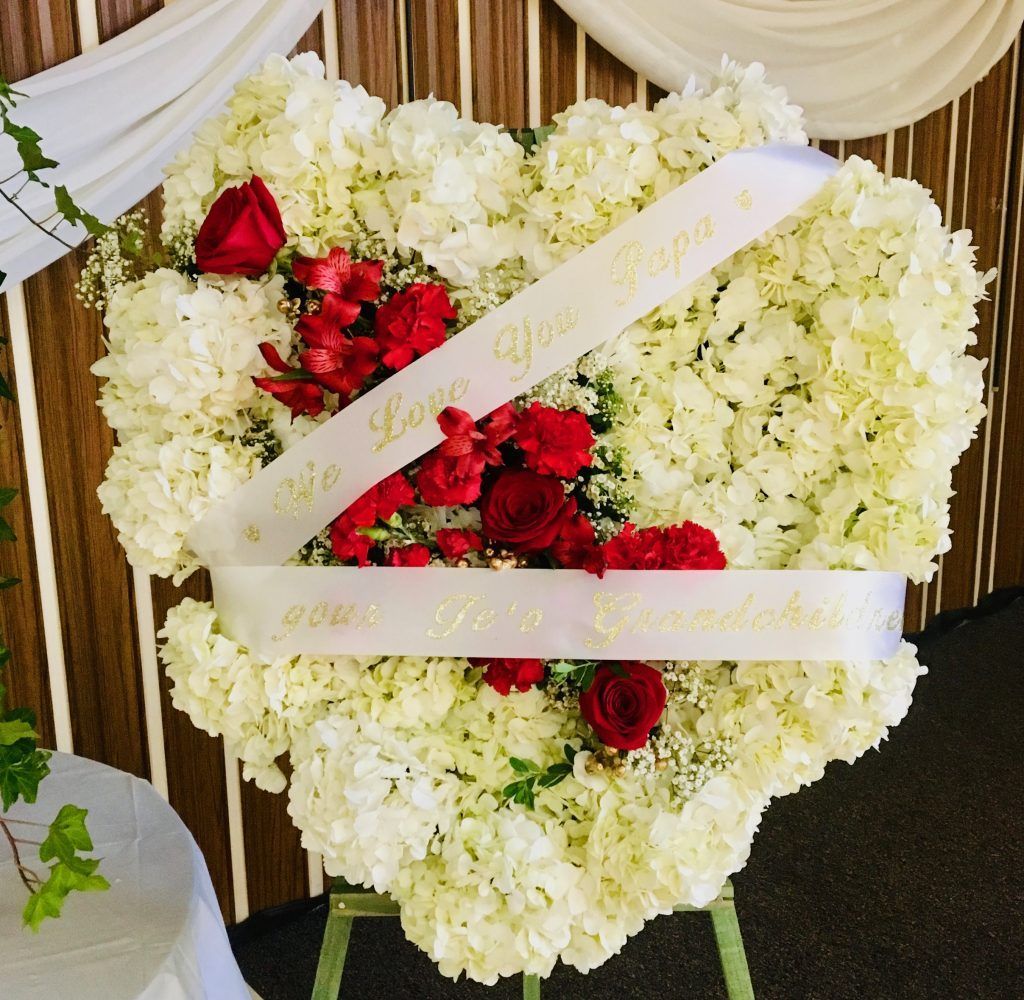 A heart shaped wreath with red roses and white flowers