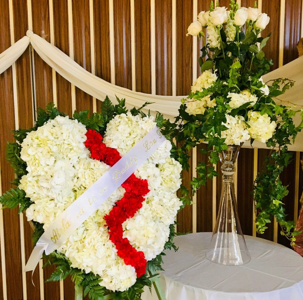 A heart made of white and red flowers with a white ribbon