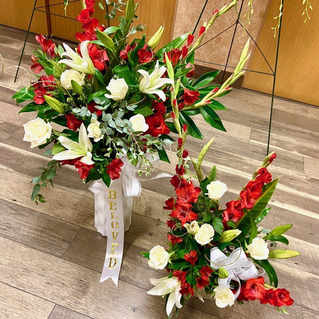 Two vases filled with red and white flowers are sitting on a wooden floor.