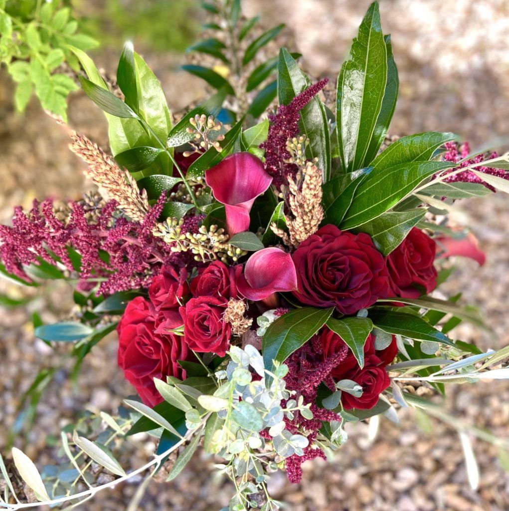 A bouquet of red roses and other flowers is sitting on the ground.
