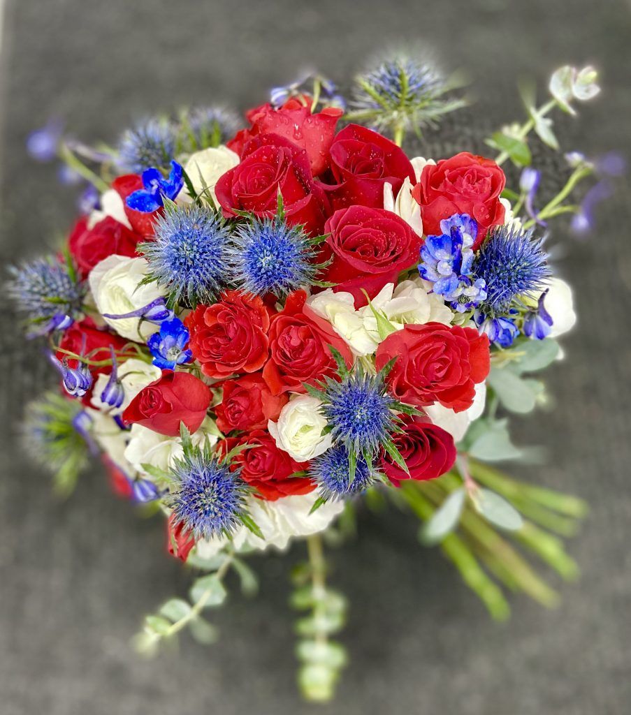 A bouquet of red , white and blue flowers on a table.