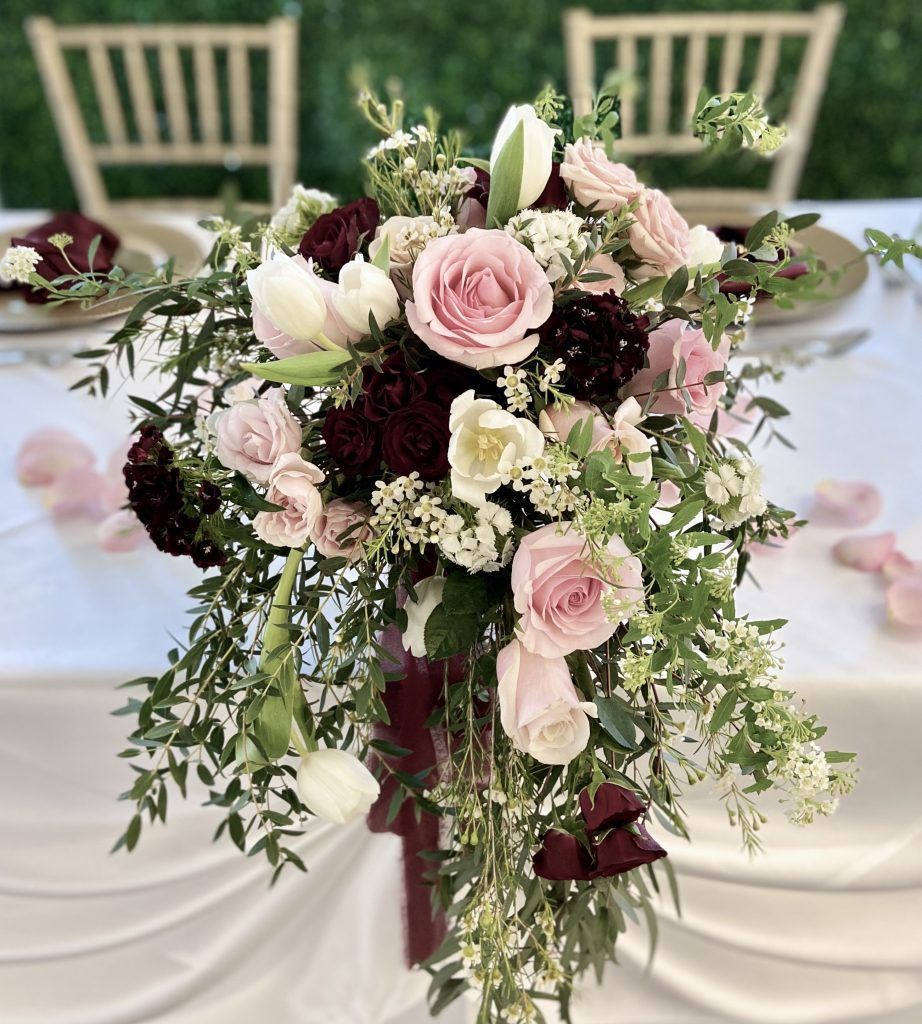 A table with a bouquet of pink and burgundy flowers on it.