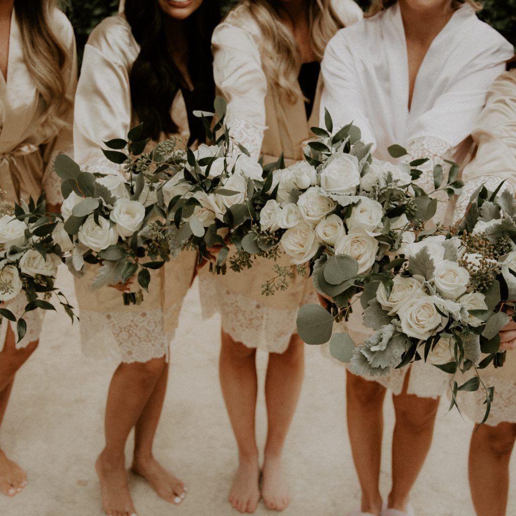 A group of women standing next to each other holding bouquets of white flowers