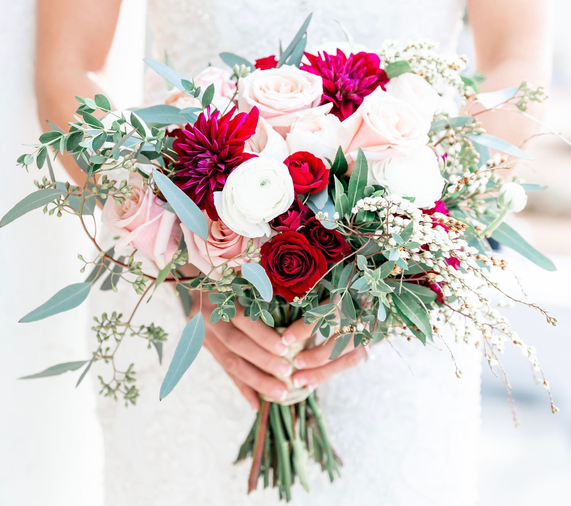 A bride is holding a bouquet of flowers in her hands.