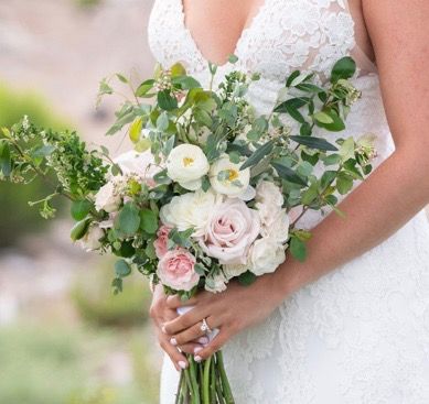 A bride in a white dress is holding a bouquet of flowers.