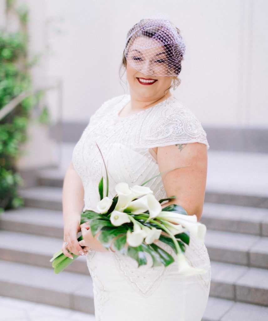 The bride is wearing a veil and holding a bouquet of flowers.