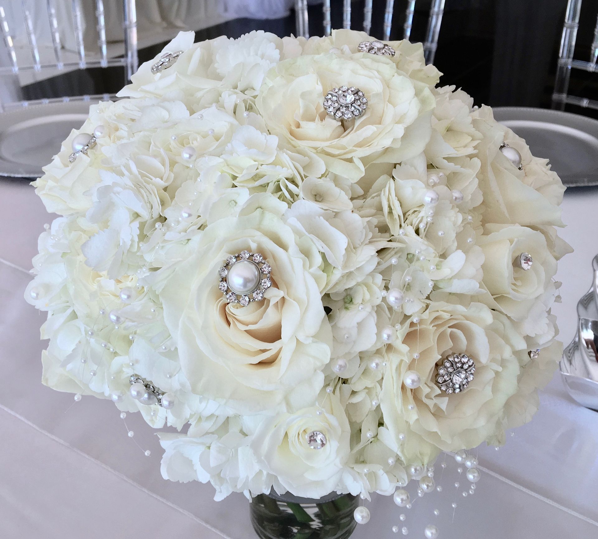A bouquet of white flowers with pearls and rhinestones on a table