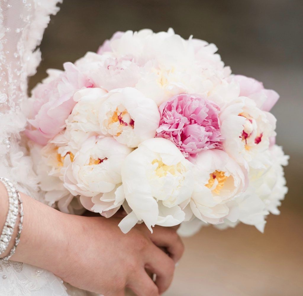 A bride is holding a bouquet of white and pink flowers.