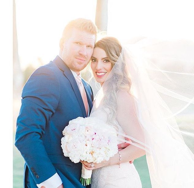 A bride and groom are posing for a picture while the bride is holding a bouquet of flowers.
