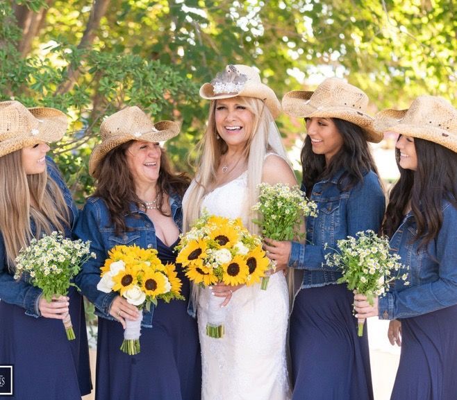 The bride and her bridesmaids are wearing cowboy hats and denim jackets