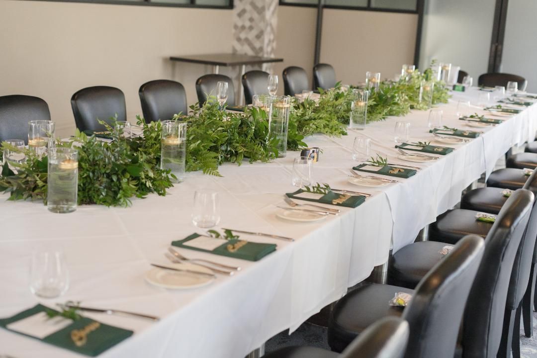 A long table with a white table cloth and candles on it.