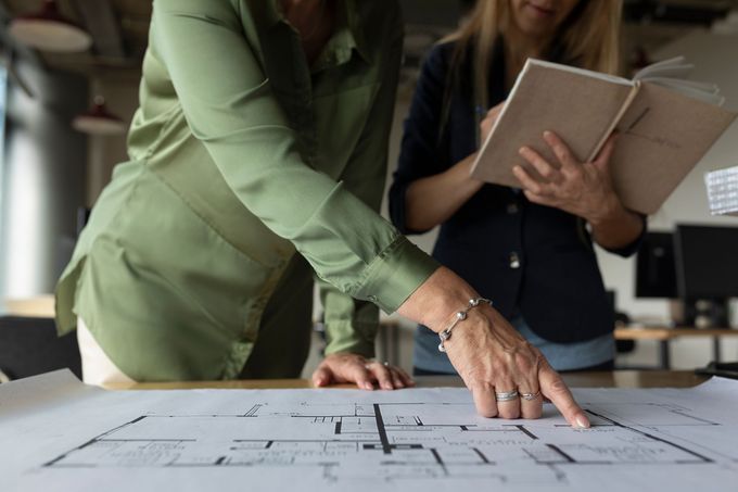Due donne stanno osservando la planimetria di un edificio.