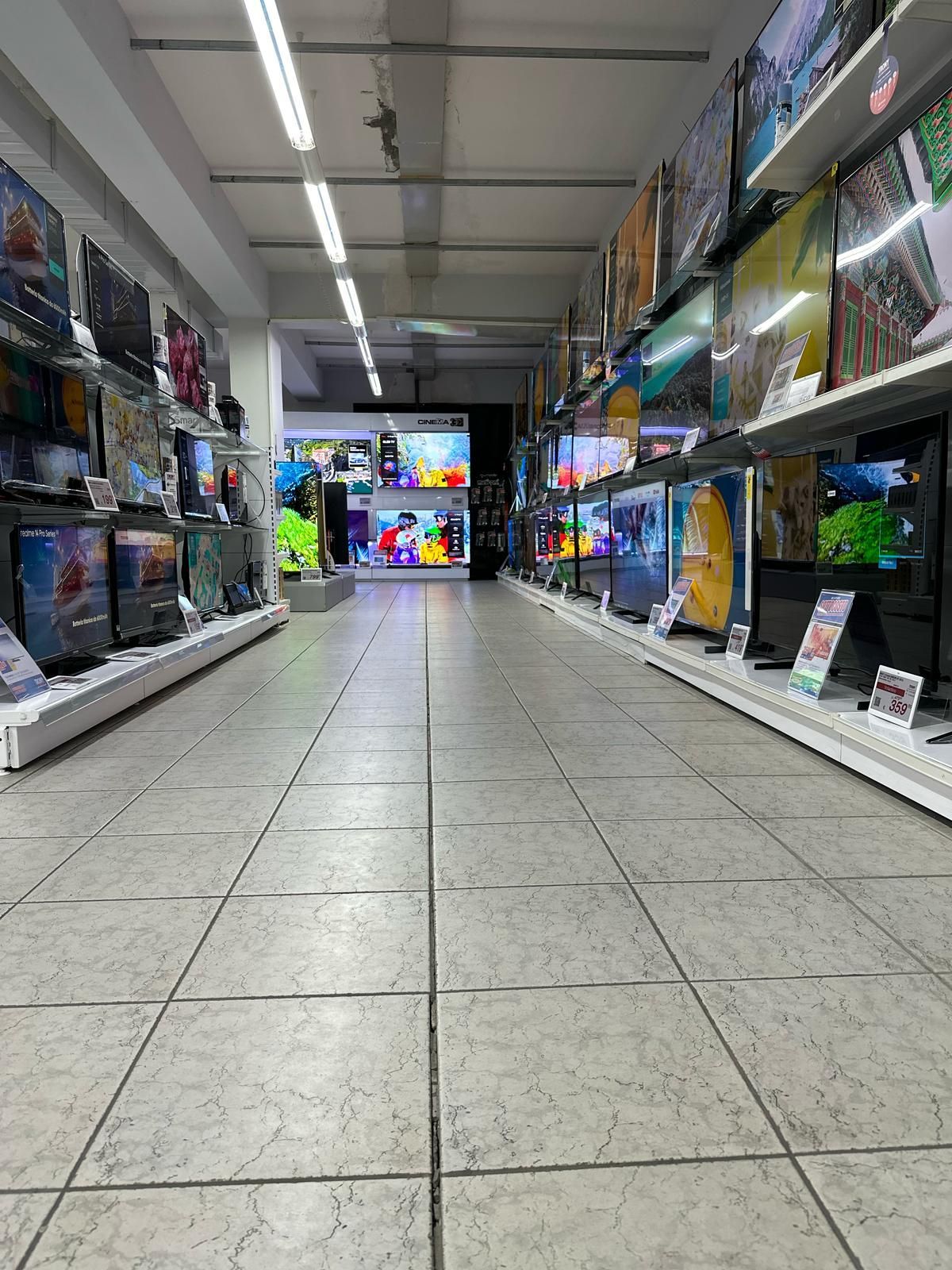 Un lungo corridoio di un negozio pieno di televisori.