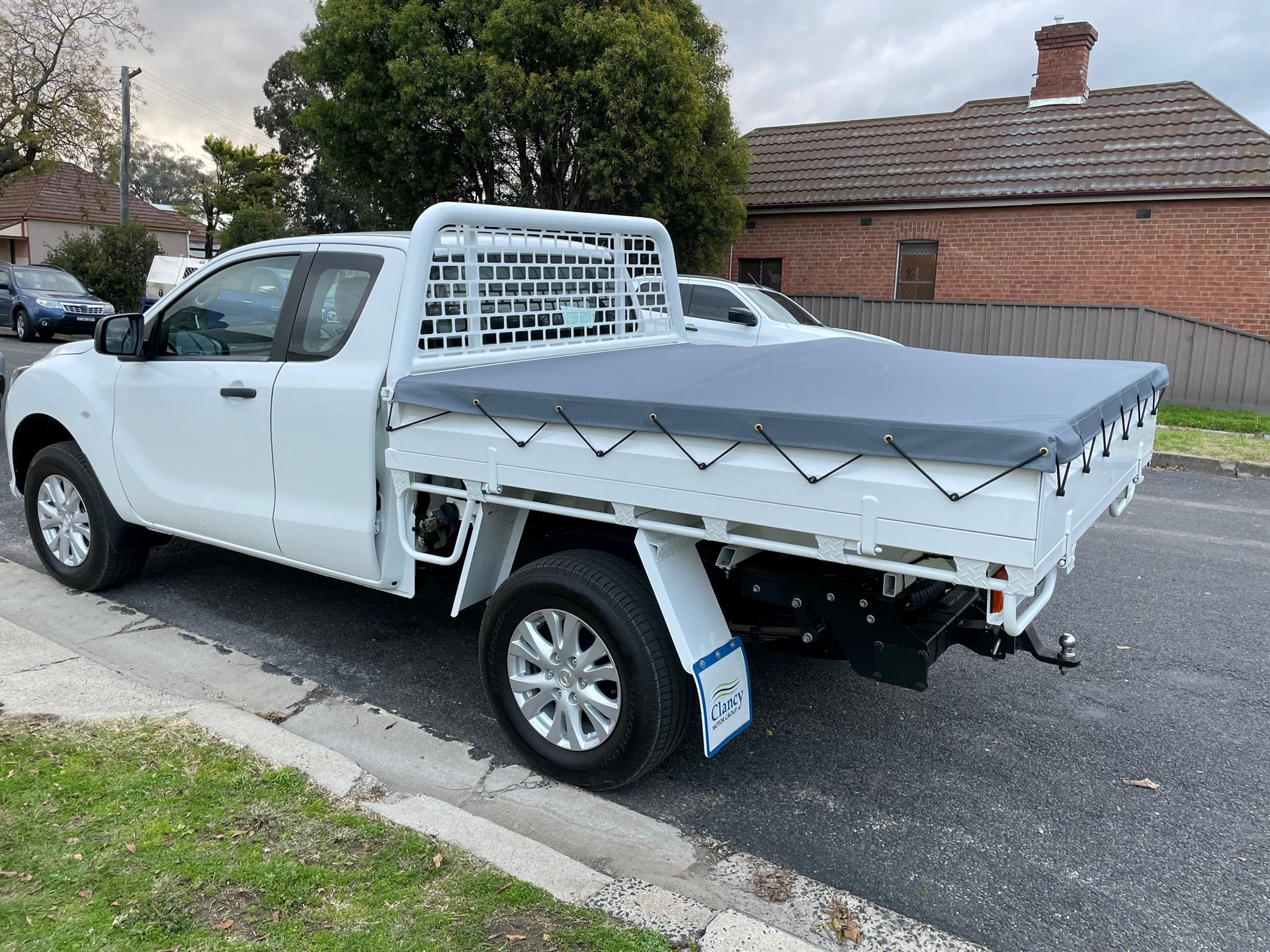 A White Ute With A Canopy Cover Is Parked On The Side Of The Road — Simmons Glass & Trim In Bathurst, NSW