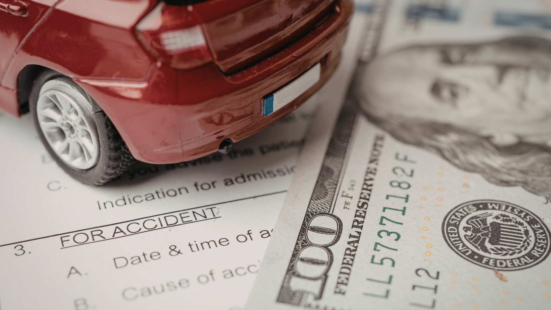 Red toy car on accident report with cash.