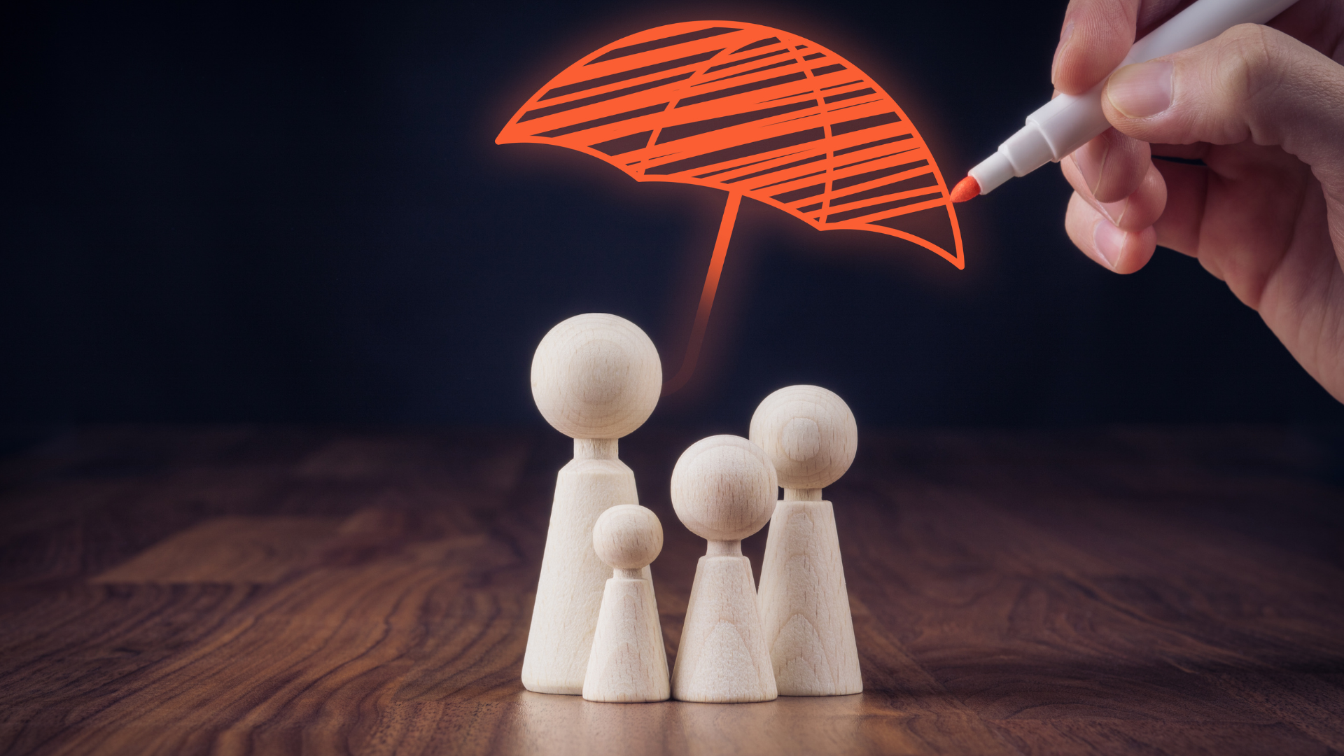 Wooden family figures under an orange umbrella drawn by a hand, symbolizing protection.