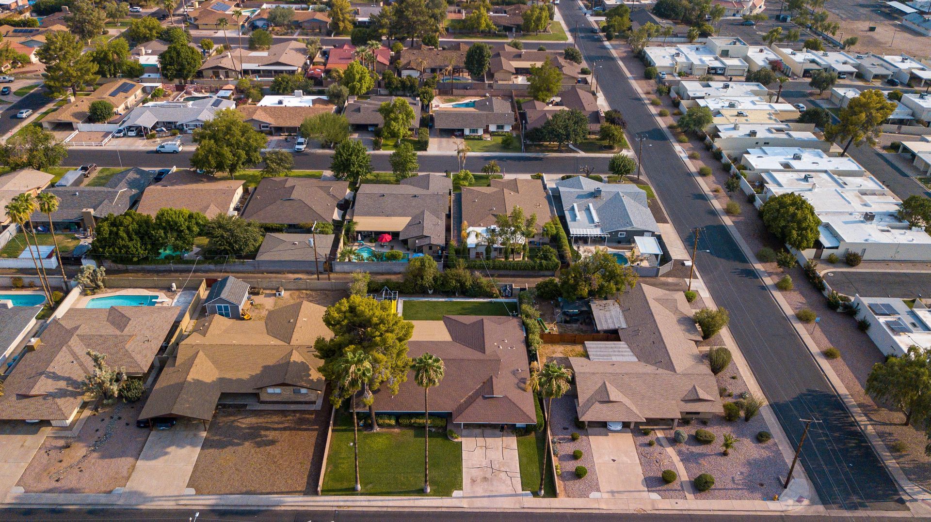 Aerial view of a Surprise AZ West Valley neighborhood: stucco homes, palm trees, backyard pools.