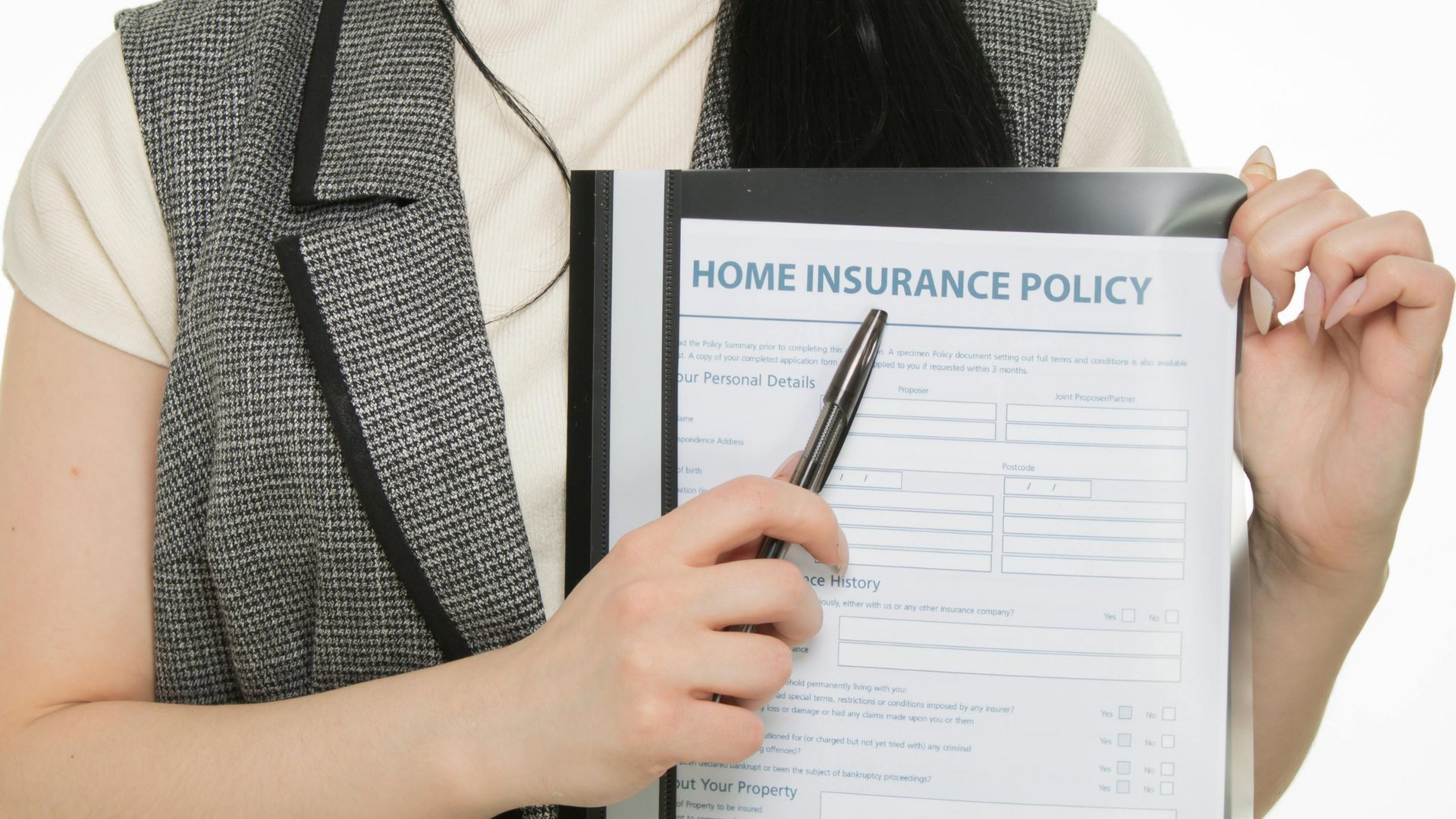 A person in a gray vest holds a black binder with a 