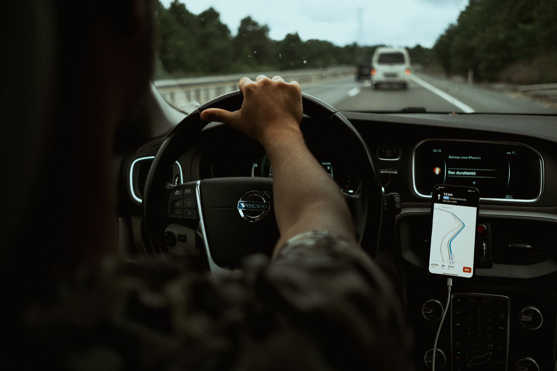 Hand on the wheel on an Arizona highway, showing telematics usage-based auto insurance for drivers.