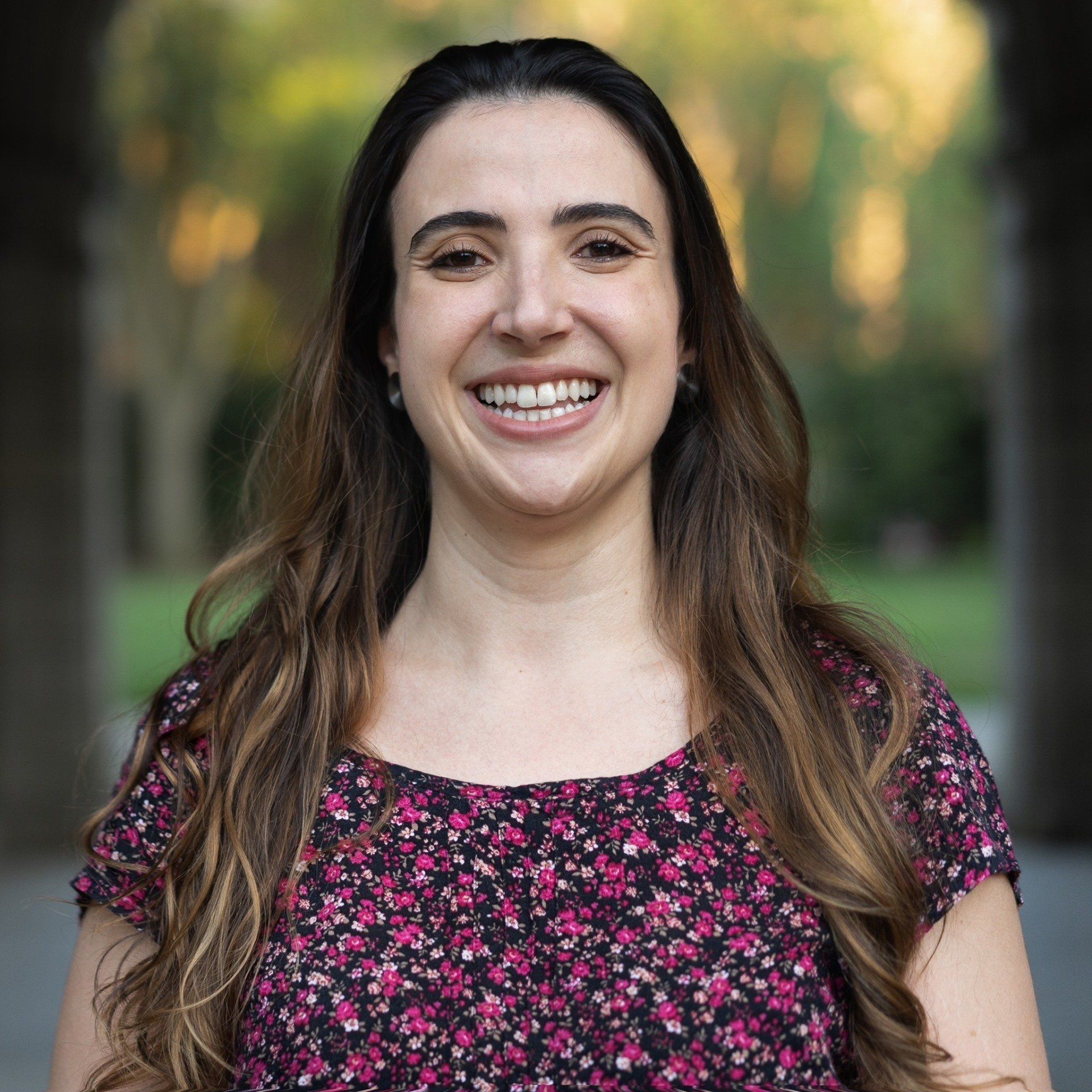 Uma mulher com uma camisa floral está sorrindo para a câmera.